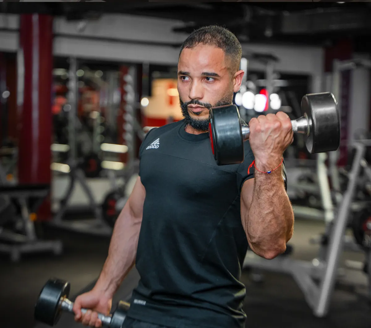 Coach en curl haltère sur le plateau musculation